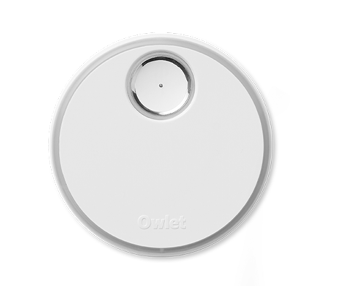 Die Owlet Dream Sock Basisstation von Owlet ist ein rundes, weißes Gerät mit einem kleinen, kreisförmigen Metallsensor an der Oberseite und einem eingeprägten "Owlet" in der unteren Mitte.