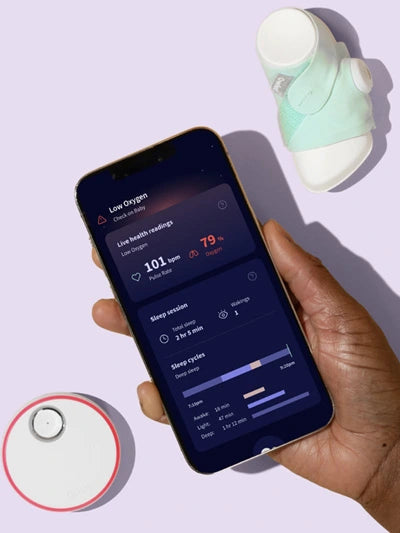 Eine Hand hält ein Smartphone, auf dem eine Gesundheitsüberwachungs-App angezeigt wird, die Sauerstoffwerte und Schlafstatistiken anzeigt. Neben dem Telefon befinden sich ein kleines tragbares Gerät, das oft als Baby-Pulsoximeter verwendet wird, und ein rundes Ladepad auf hellviolettem Hintergrund.