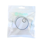 In einer versiegelten, transparenten Plastiktüte befindet sich die Owlet Dream Sock Basisstation mit einem kreisförmigen Sensor und dem Owlet-Logo mit dem Text "Rest Assured" auf der Verpackung.