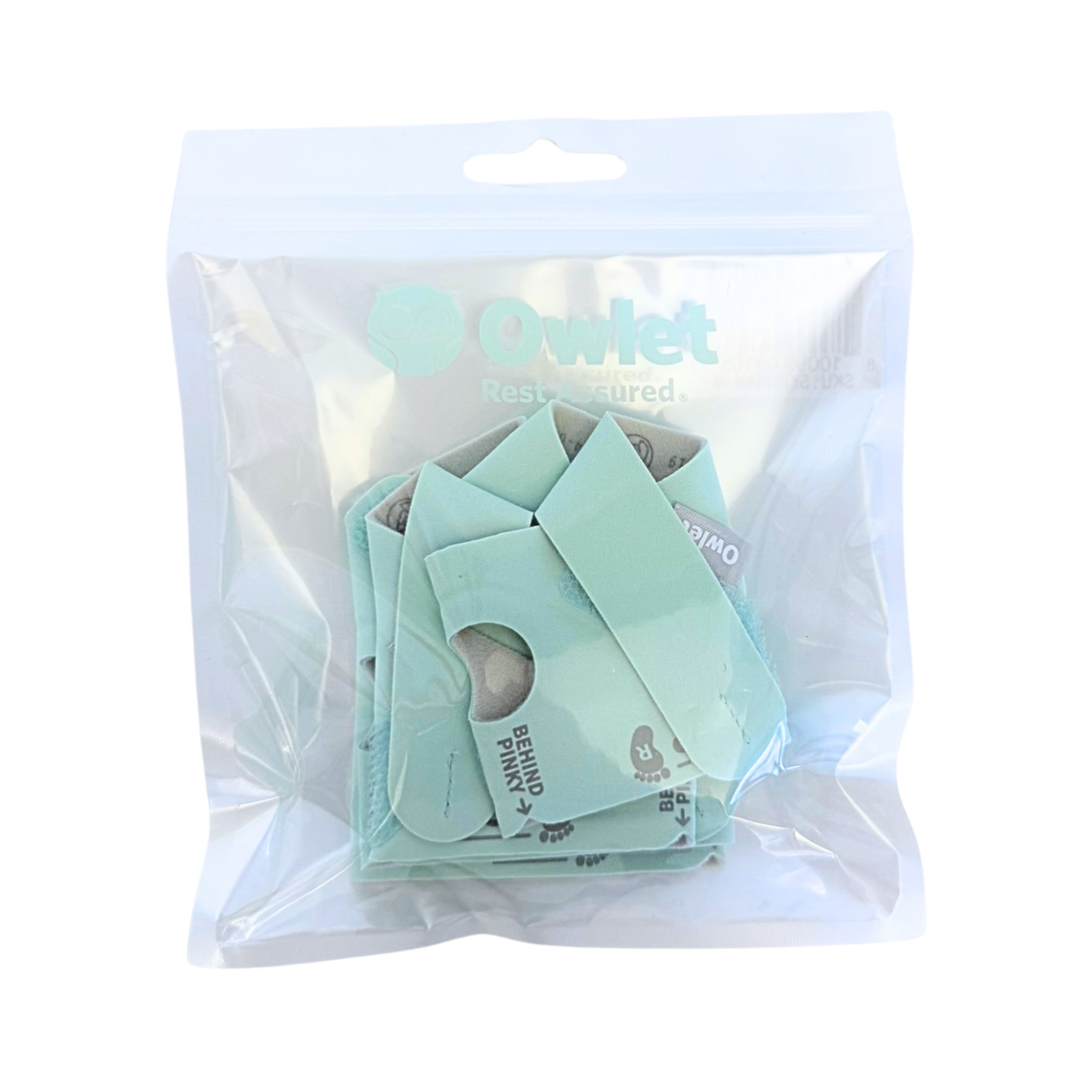 Eine durchsichtige Plastiktüte enthält das Owlet Dream Sock Set Mint (Gr. 1 + Gr. 2) Babyphone-Socken von Owlet mit ausgeschnittenen Löchern und Branding auf weißem Hintergrund.