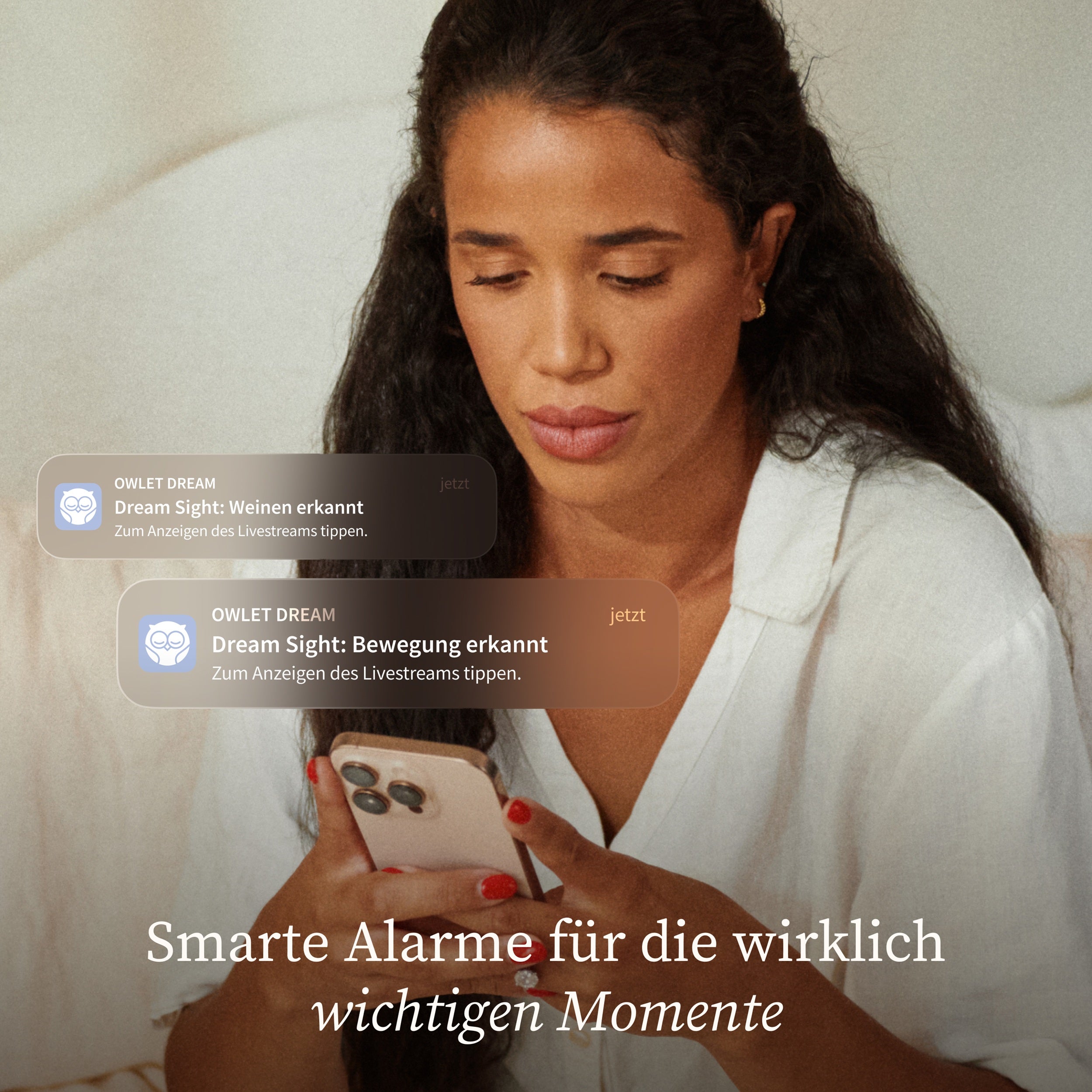 Eine Frau mit langen dunklen Haaren schaut auf ihr Smartphone und erhält von der Owlet Dream Sight intelligente 2K HD-Benachrichtigungen über die Schreie und Bewegungen ihres Babys: Neue 2K HD Babyphone Kamera von Owletcare.de. Text unten: "Smarte Alarme für die wirklich wichtigen Momente.
