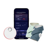 Ein Smartphone, auf dem eine Gesundheitsüberwachungs-App angezeigt wird, die „Owlet Dream Sock“ mit Ersatzsocke von Owletcare.de – ein weißes, rundes Gerät sowie zwei Stoff-Babyschühchen mit integrierter Elektronik in Grün und Blau – sind zur Echtzeitüberwachung auf einem weißen Hintergrund angeordnet.