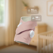 Die „Owlet Dream Sock“ mit Ersatzsocke von Owletcare.de, hier in Rosa abgebildet, zeigt eine Herzfrequenz von 91 Schlägen pro Minute und einen Sauerstoffgehalt von 98 % an. Das tragbare Babyfon schwebt in einem sanft beleuchteten Kinderzimmer, im Hintergrund sind ein Kinderbett und Wandbilder zu sehen.